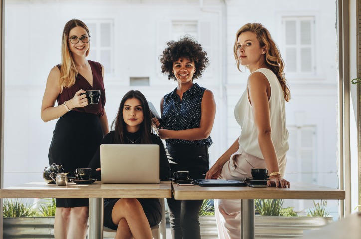 Mulheres reunidas em frente a uma mesa de escritório